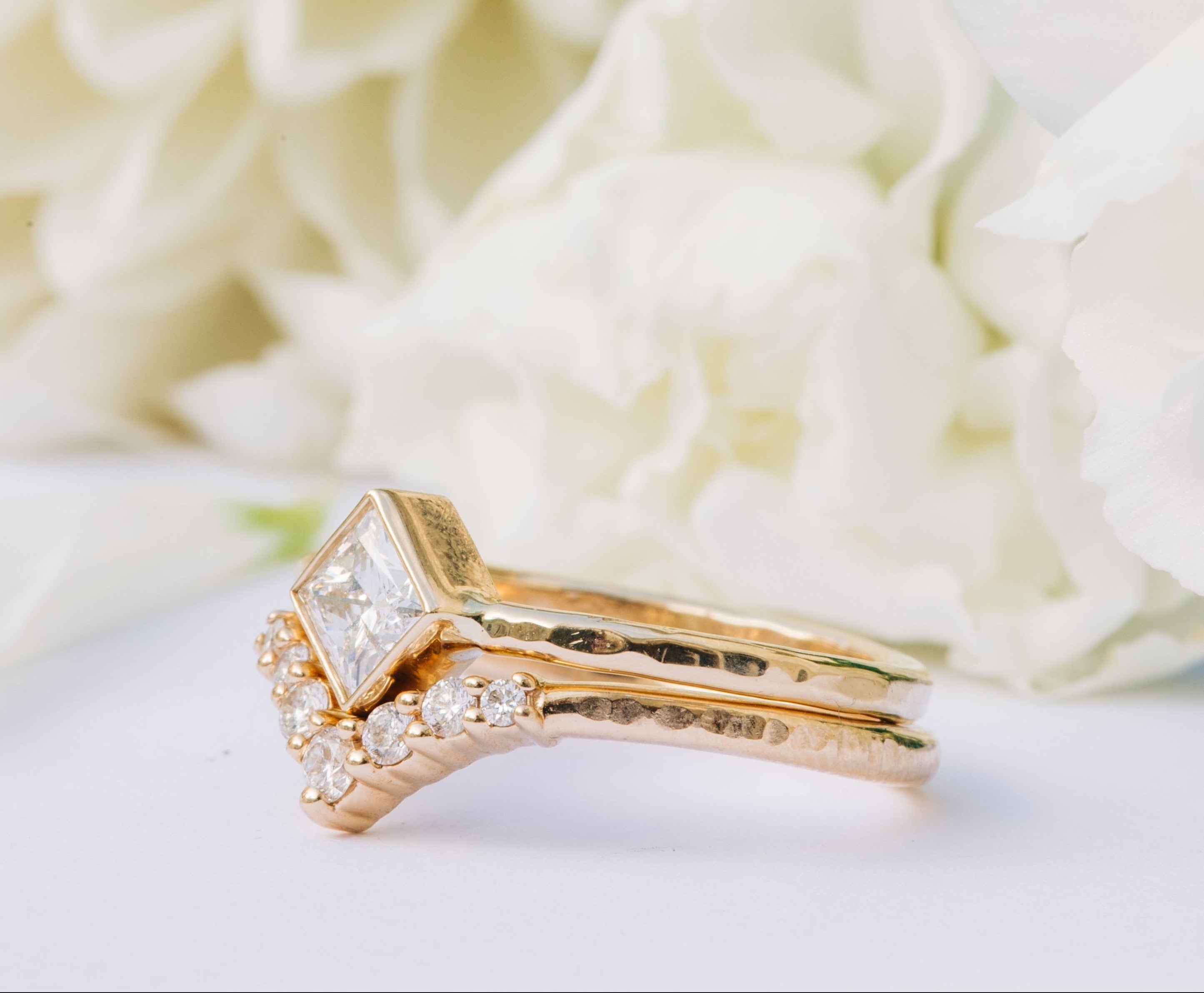 Gold ring with diamond accents on a white floral background