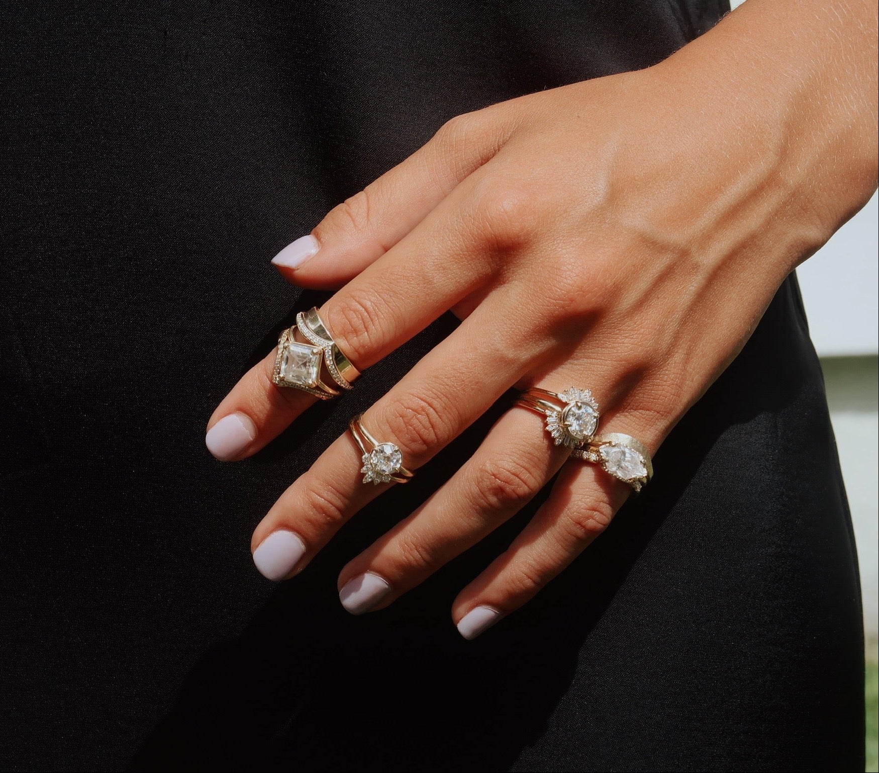 Close-up of a hand wearing multiple diamond rings on a black background