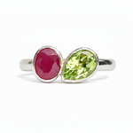 Silver ring with a red gemstone and a green gemstone on a white background