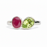 Silver ring with a red gemstone and a green gemstone on a white background