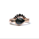 Rose gold ring with black gemstones on a white background