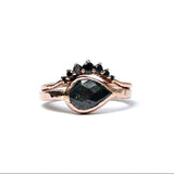 Rose gold ring with black gemstones on a white background