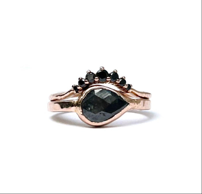 Rose gold ring with black gemstones on a white background